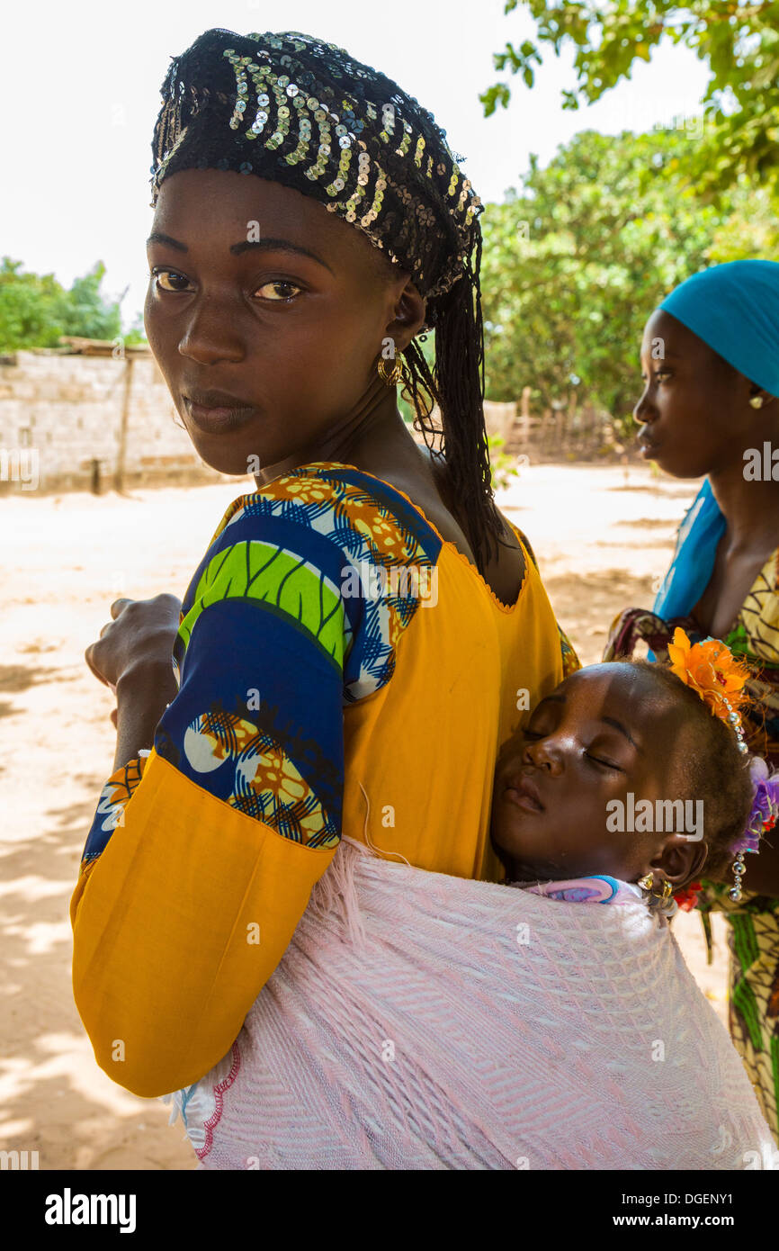 Giovane madre gambiana portando la figlia a Pelo sul dorso, Fass Njaga Choi, banca del Nord della regione, il Gambia. Foto Stock