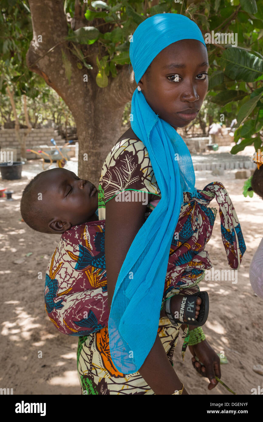 I giovani della Gambia portante madre figlio che dorme sul retro, Fass Njaga Choi, banca del Nord della regione, il Gambia. Foto Stock