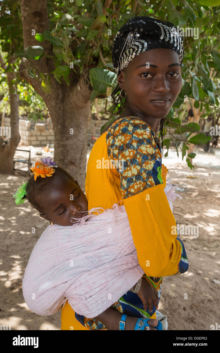 Giovane madre gambiana portando la figlia a Pelo sul dorso, Fass Njaga Choi, banca del Nord della regione, il Gambia. Foto Stock