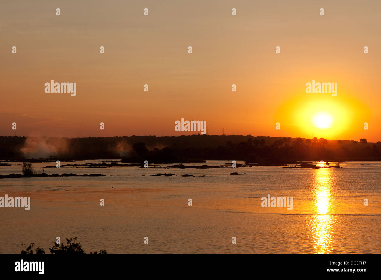 Tramonto africano oltre il fiume Zambesi, spray da Victoria Falls a sinistra dell'immagine, dello Zambia in Africa Foto Stock