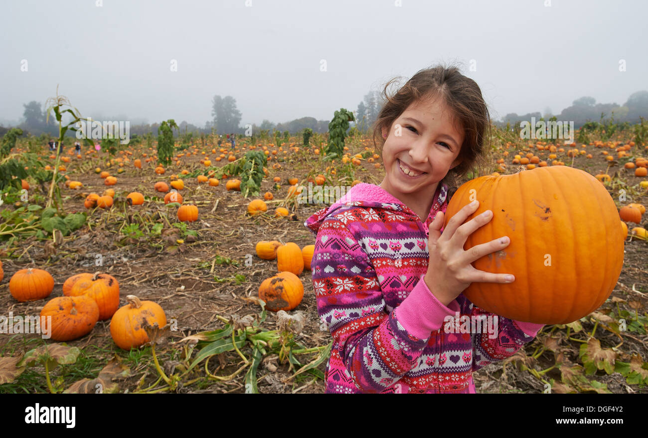 Una ragazza alla zucca patch scegliendo una zucca di Halloween. Foto Stock