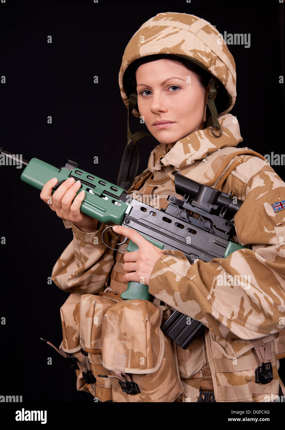 Giovani donne soldato Holding SA80 fucile e indossando militare inglese desert camouflage uniforme. Foto Stock