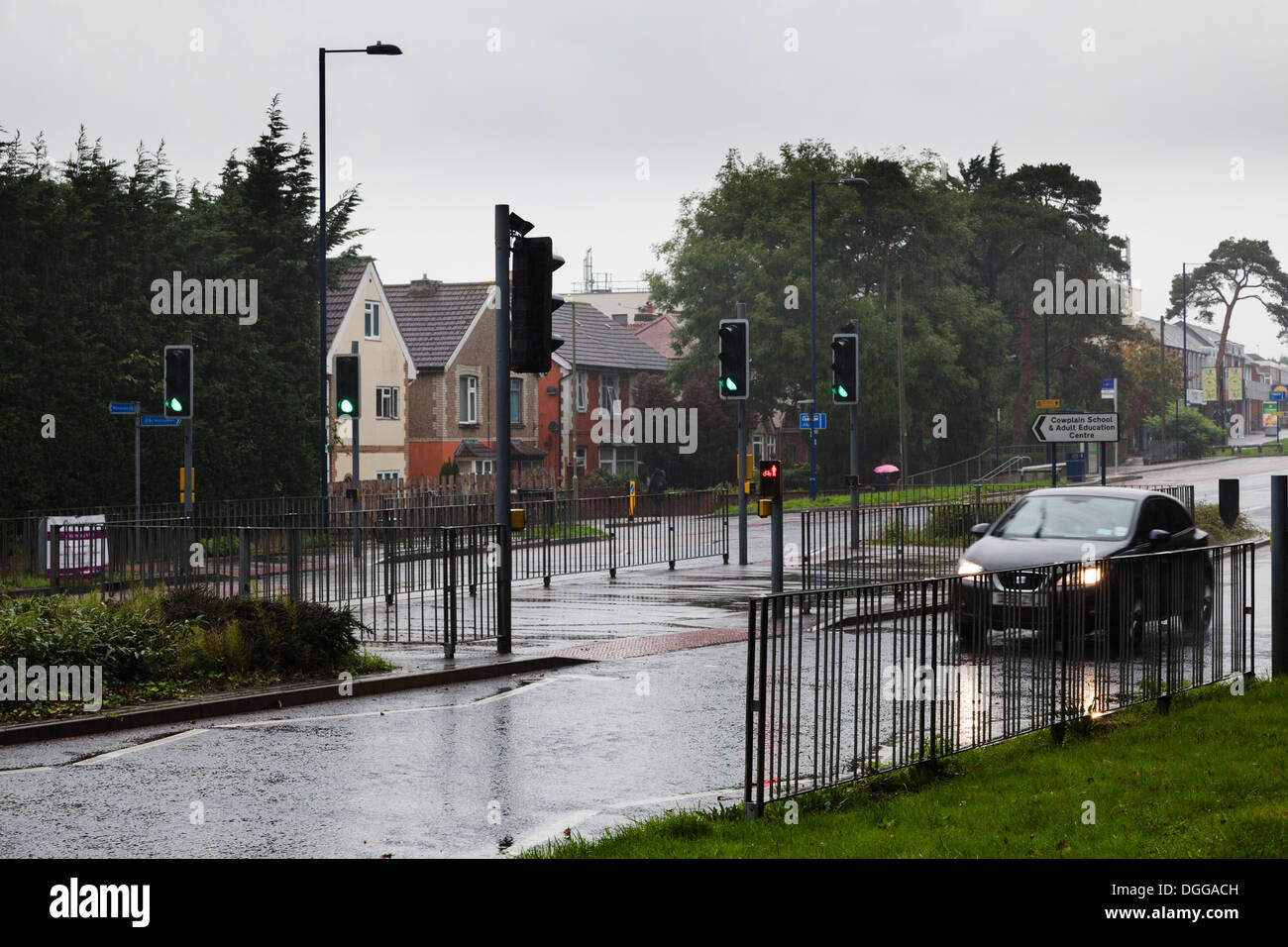 Auto sulla strada delle piogge con luci controllate sfalsati pellicano pedonale di attraversamento Foto Stock