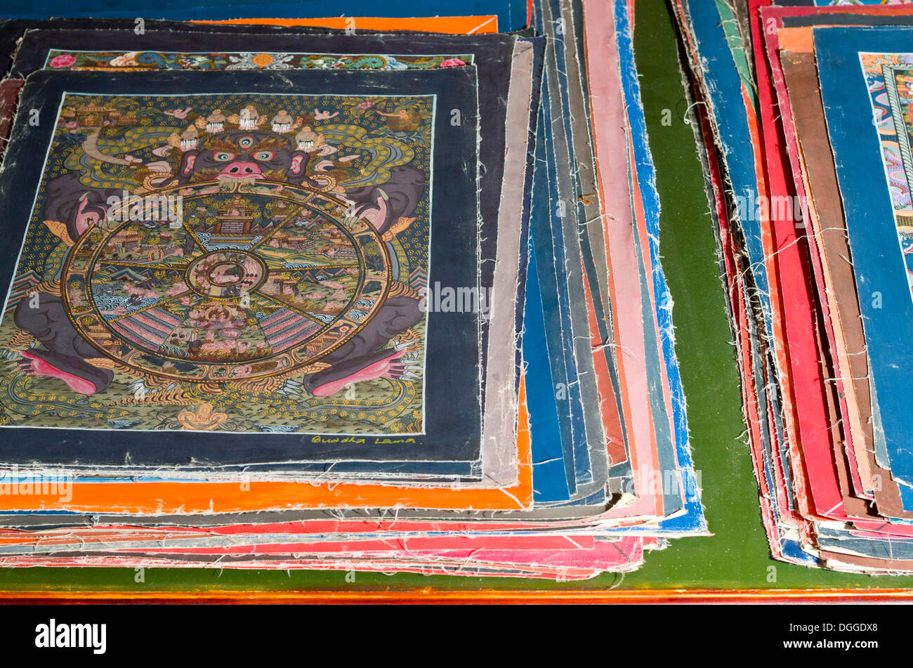 Pila di piccole Thangkas in vendita in una delle scuole di arte vicino Boudnath Stupa, Valle di Kathmandu, Kathmandu, Distretto di Kathmandu Foto Stock