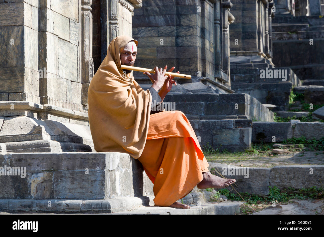 Giovane uomo la riproduzione di flauto a combustione ghats, Kathmandu, Distretto di Kathmandu, zona di Bagmati, Nepal Foto Stock