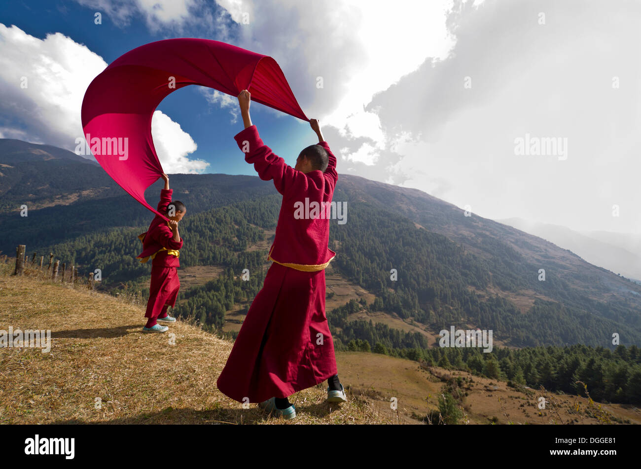 Giovani monaci indossando panni rosso aquilone volante con una coperta su un pendio, Junbesi, Solukhumbu quartiere Zona Sagarmāthā Foto Stock