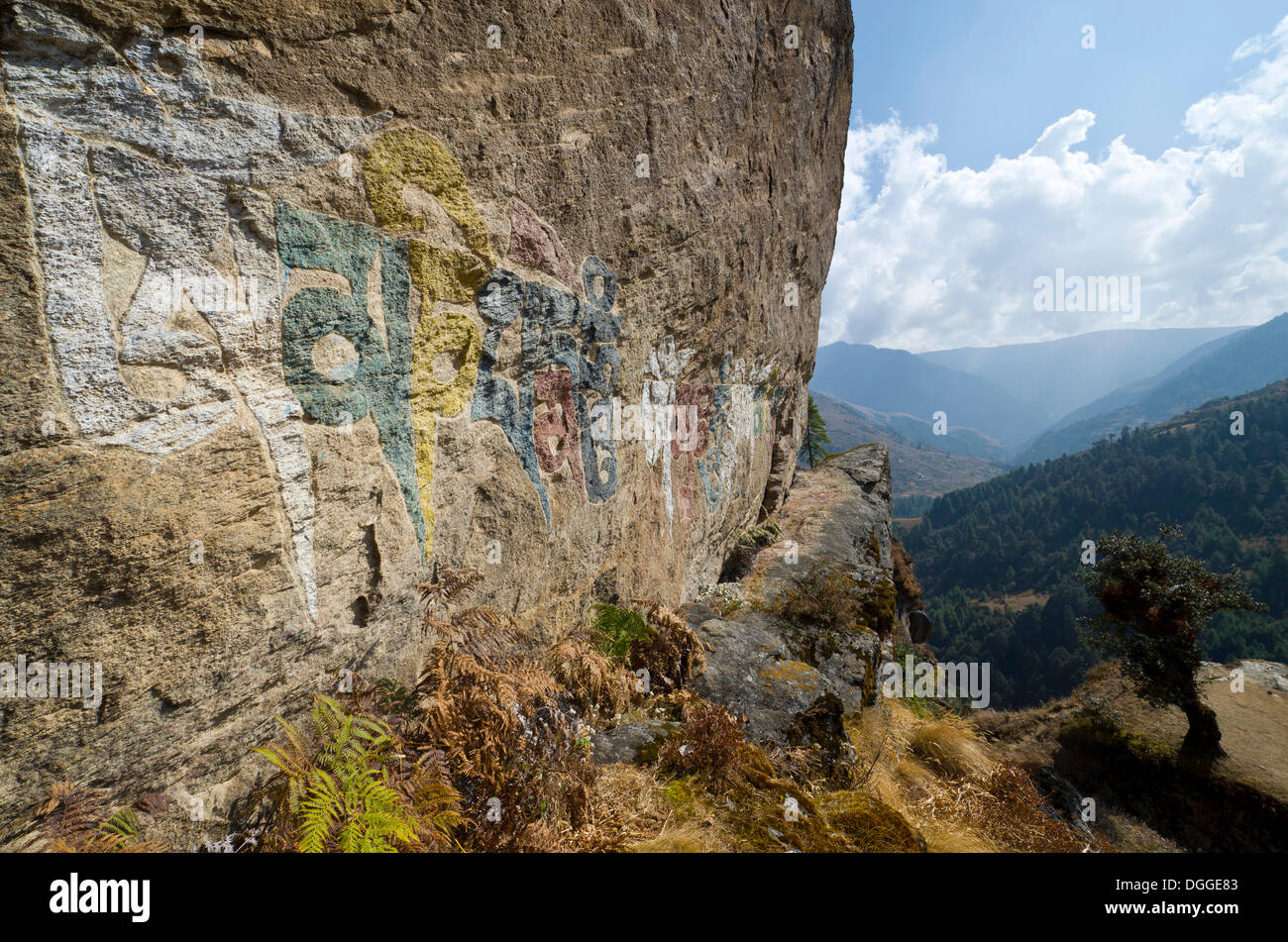 "Om mani padme hum' mantra dipinto ad una grande roccia, montagne sullo sfondo, Junbesi, Solukhumbu quartiere Zona Sagarmāthā Foto Stock