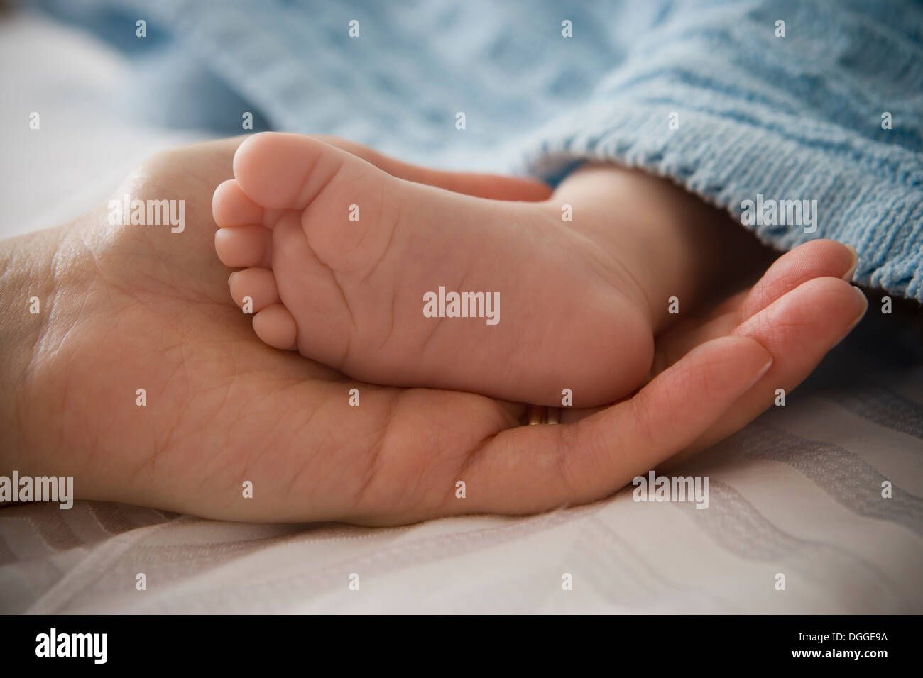 Metà donna adulta holding baby boy il piede Foto Stock
