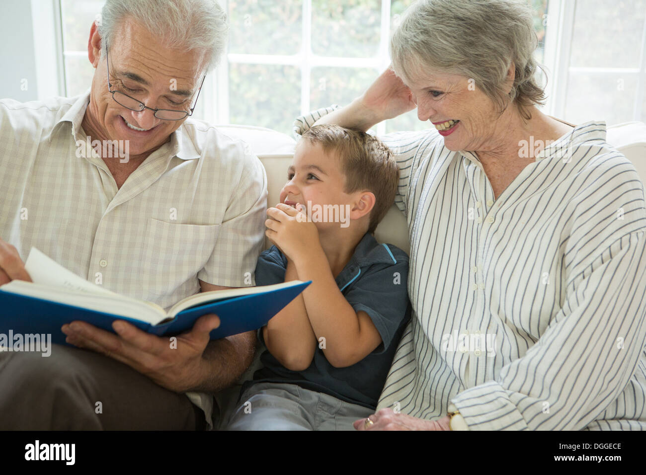 Nonni che mostra boy album di foto sul divano Foto Stock