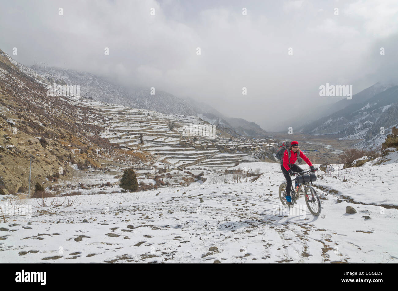 Ciclista in sella alla sua moto nella neve fino verso Thorong La Pass (5416 m), Manang, Regione di Annapurna, Nepal Foto Stock