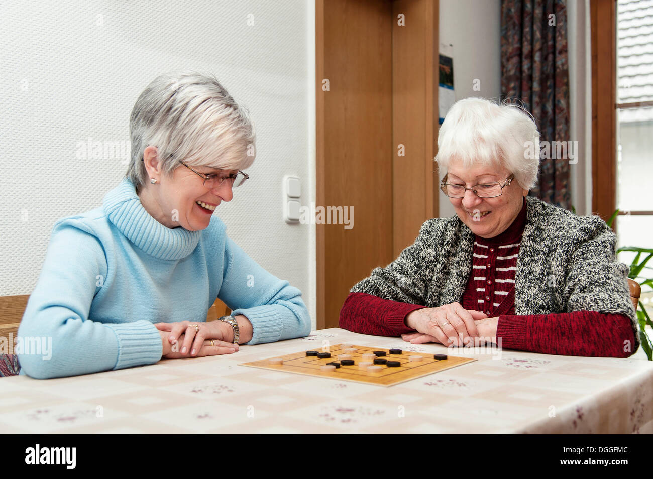 Due donne anziane, cittadini anziani, madre e figlia, giocando il gioco di bordo "nove uomini Morris', Rehna Foto Stock