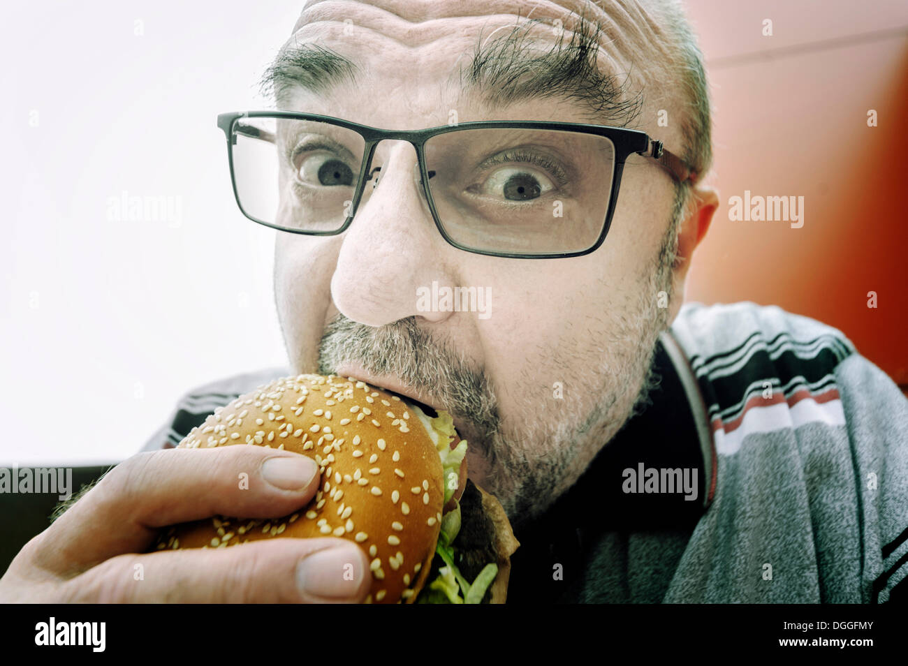 Uomo di mangiare un hamburger, Germania Foto Stock