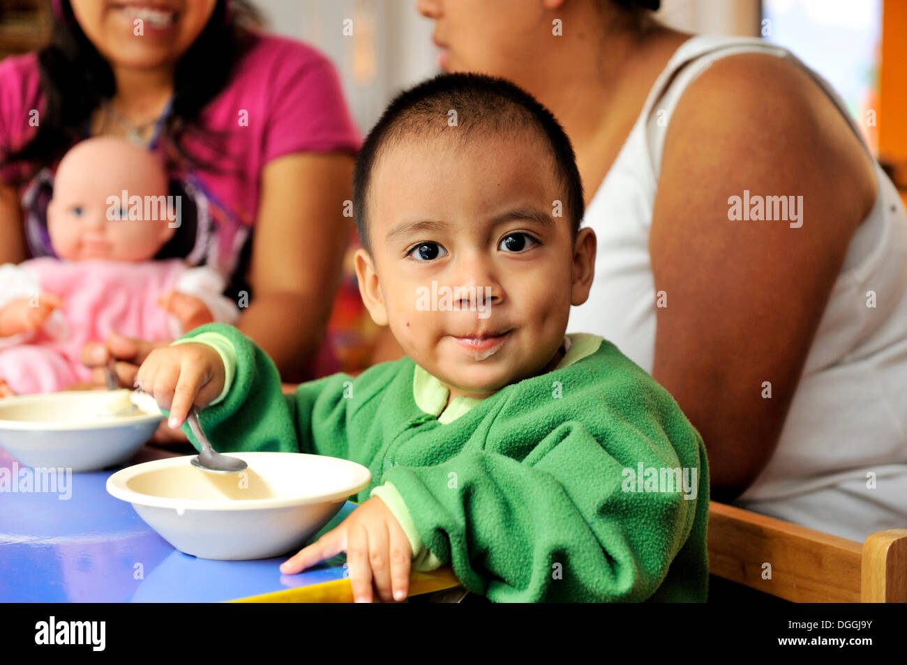Ragazzo con un look vivace di mangiare il porridge, madre-bambino gruppo in Puebla, Messico, America Centrale Foto Stock