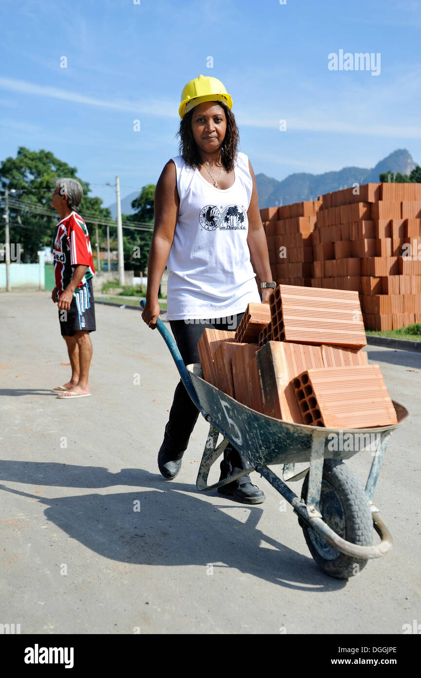 Una donna dalla baraccopoli, favelas, trasporto di mattoni in una carriola su un sito di costruzione della 'Esperanca' alloggiamento co-operativa, Foto Stock