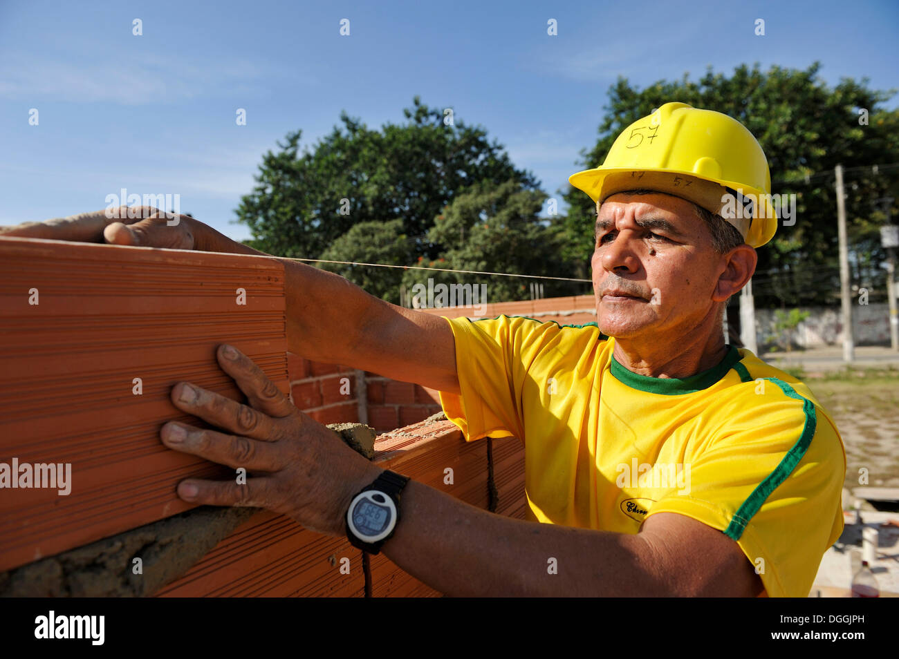 Uomo con un elmetto lavorando su un sito di costruzione della 'Esperanca' alloggiamento co-operativa, ogni famiglia di aiutare con il progetto Foto Stock