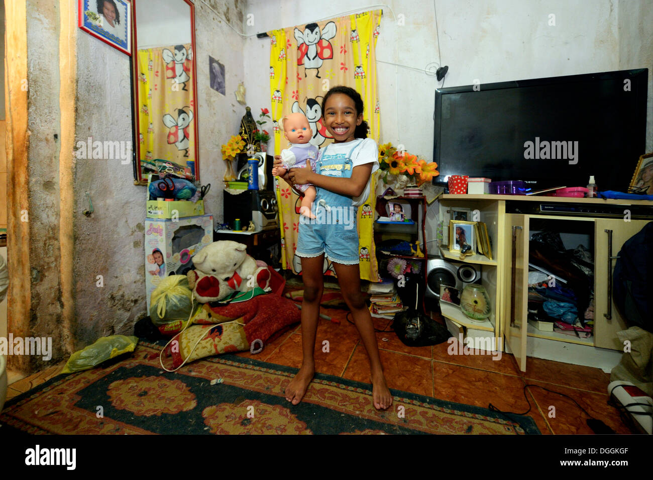Ragazza, sorridente, tenendo una bambola in un appartamento in una delle baraccopoli o favela, Jacarezinho favela, Rio de Janeiro, Stato di Rio de Janeiro Foto Stock