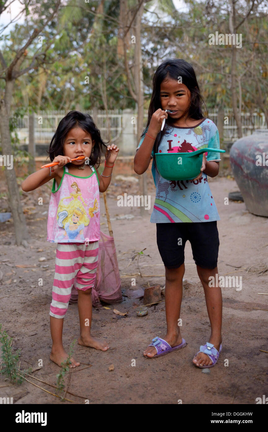 Due ragazze lavarsi i denti al di fuori di una casa di educazione all igiene, Lompong comune, Bathi Distretto, Provincia di Takéo, Cambogia Foto Stock