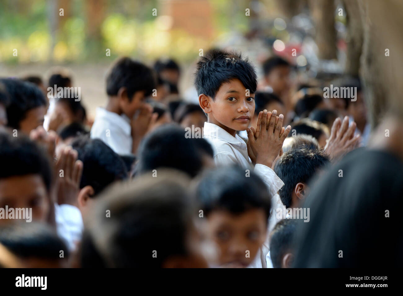 La scuola dei bambini nel preparare in preghiera per la donazione di cibo e di denaro per i monaci buddisti, tradizionale cerimonia come parte del Foto Stock