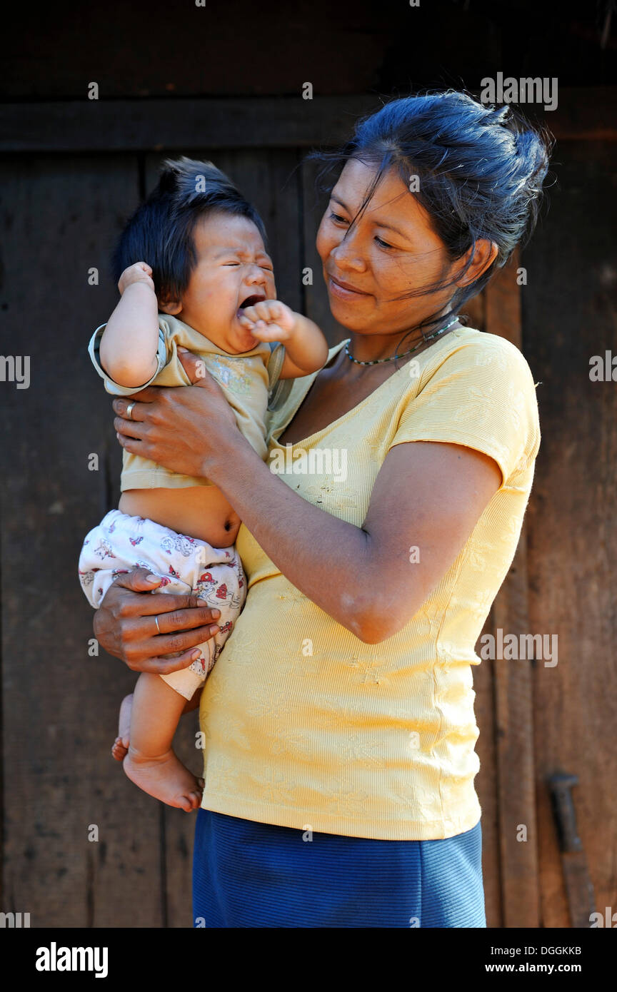 Giovane madre tenendo un pianto bambino in braccio, in una comunità di Indiani Guarani, Jaguary, Caaguazú Reparto, Paraguay Foto Stock