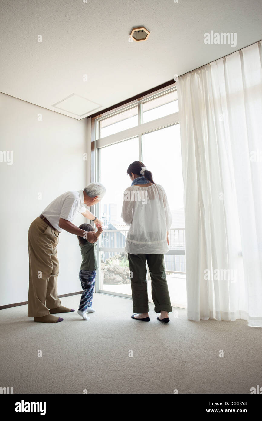 Tre generazioni la famiglia in piedi da una finestra Foto Stock