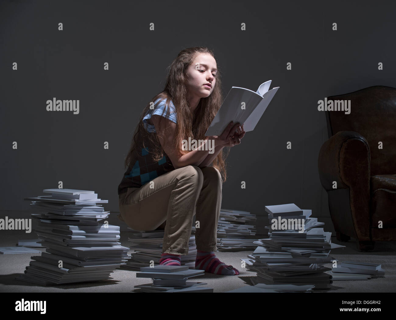 Ragazza seduta sulla pila di lettura di libri Foto Stock