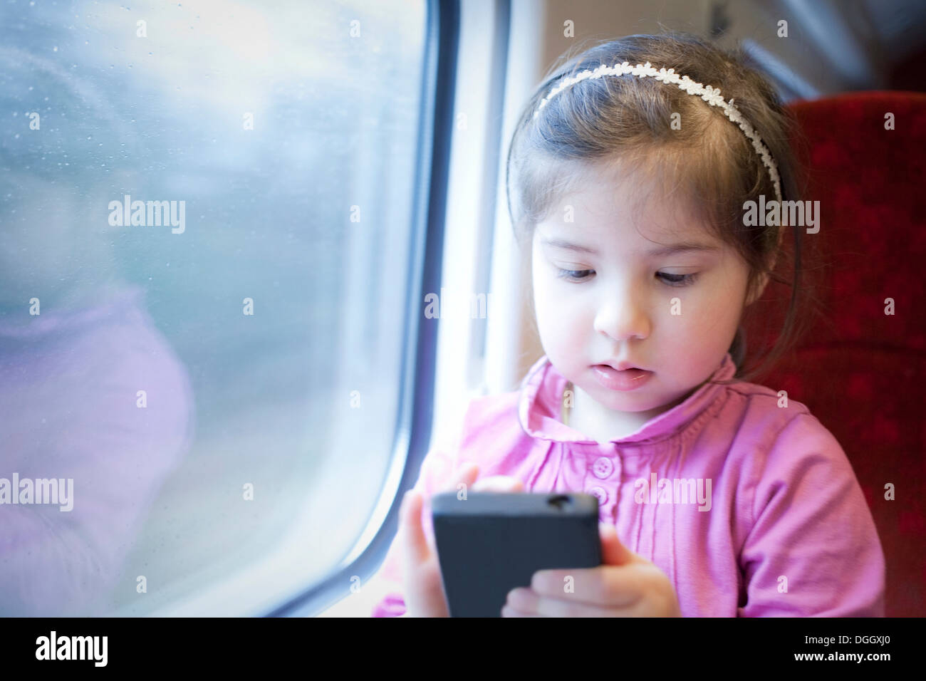 Bambina sul treno, giocando sullo smartphone Foto Stock
