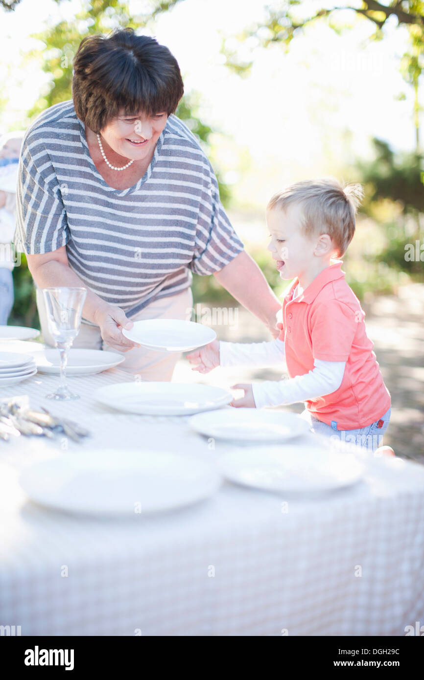 Ragazzo e la nonna impostazione tavolo per la cena all'aperto Foto Stock