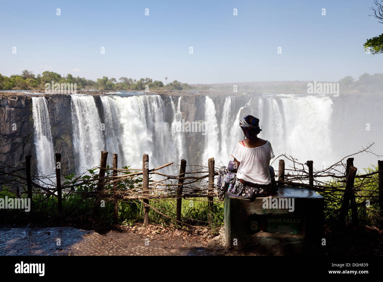 Una donna locale dallo Zimbabwe guardando i principali cataratta, Victoria Falls, il Parco Nazionale, Zimbabwe Africa Foto Stock