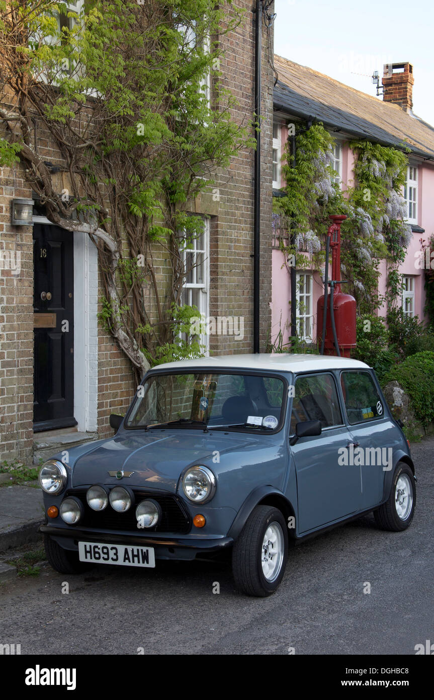 Classic car. Una Austin Mini parcheggiata nella strada alta del pittoresco villaggio di Dorset di Sydling St Nicholas. Dietro di esso è un vintage pompa benzina. In Inghilterra. Foto Stock