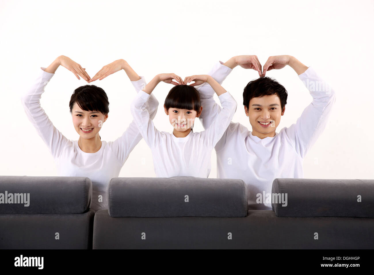 Oriente famiglia asiatica con un bambino seduto sul divano, mettendo a forma di cuore Foto Stock