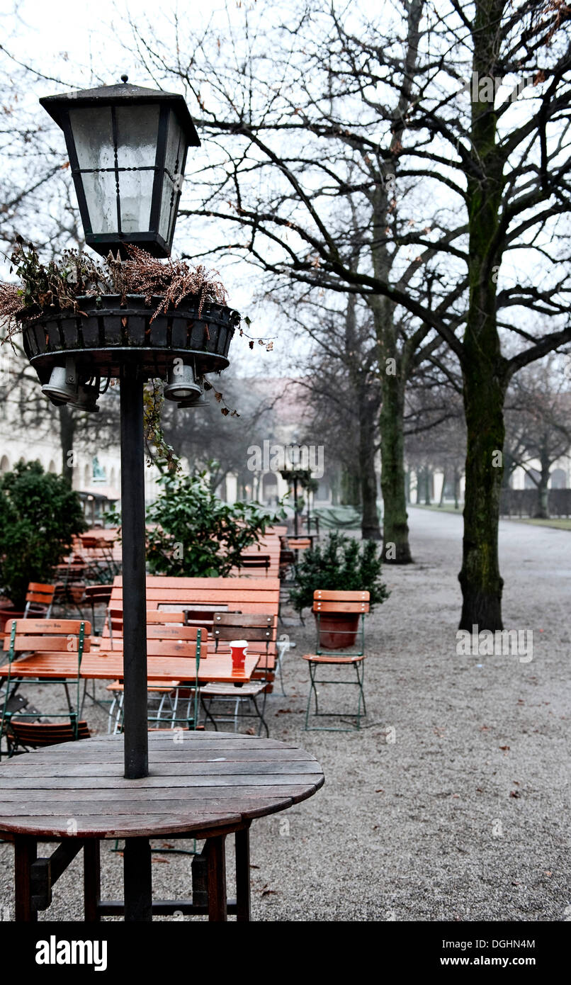 Una lampada e svuotare i tavoli e le sedie in inverno, Corte Giardino, Monaco di Baviera Foto Stock