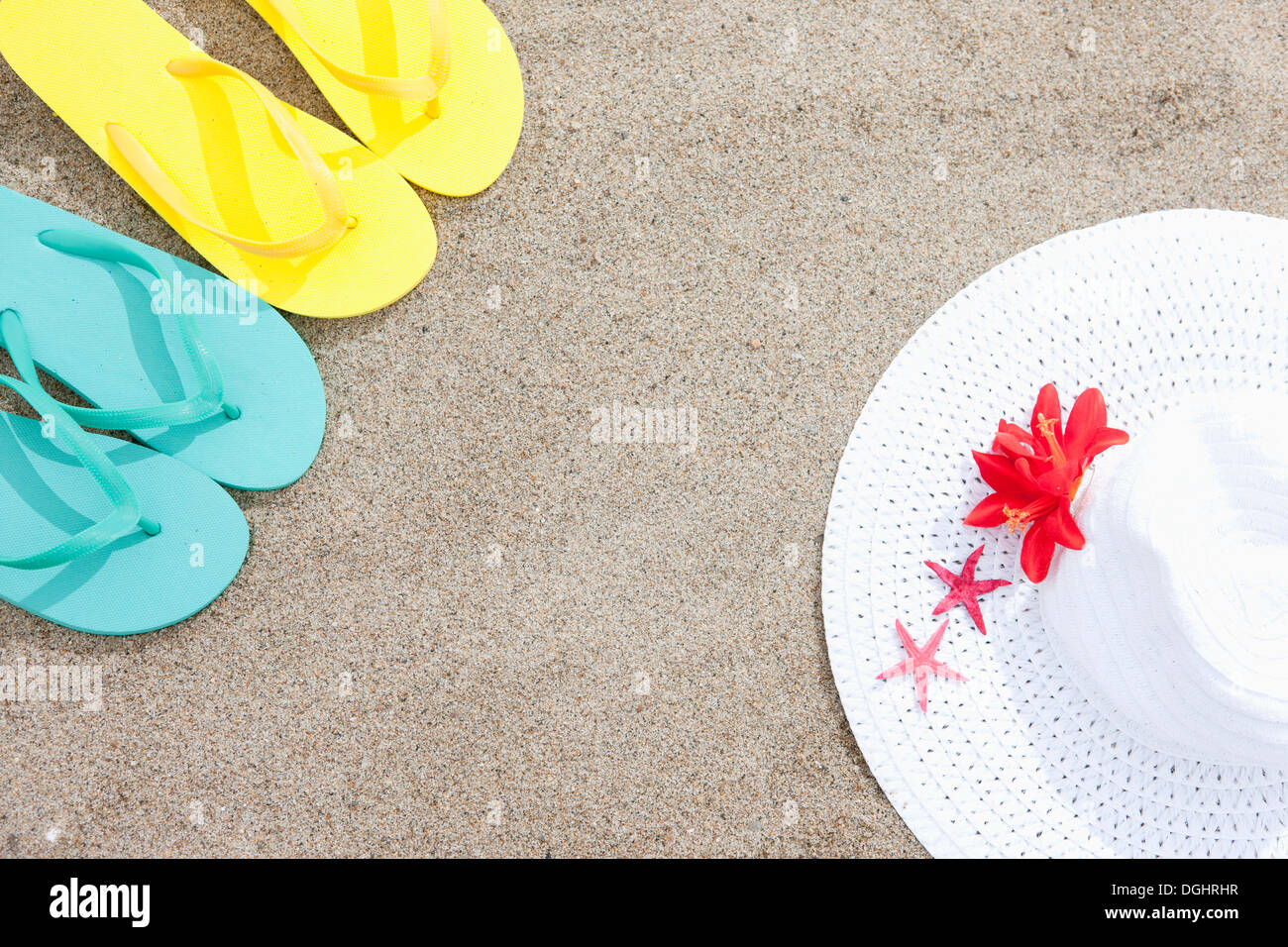 Due coppie di flip flop e un cappello su una spiaggia Foto Stock