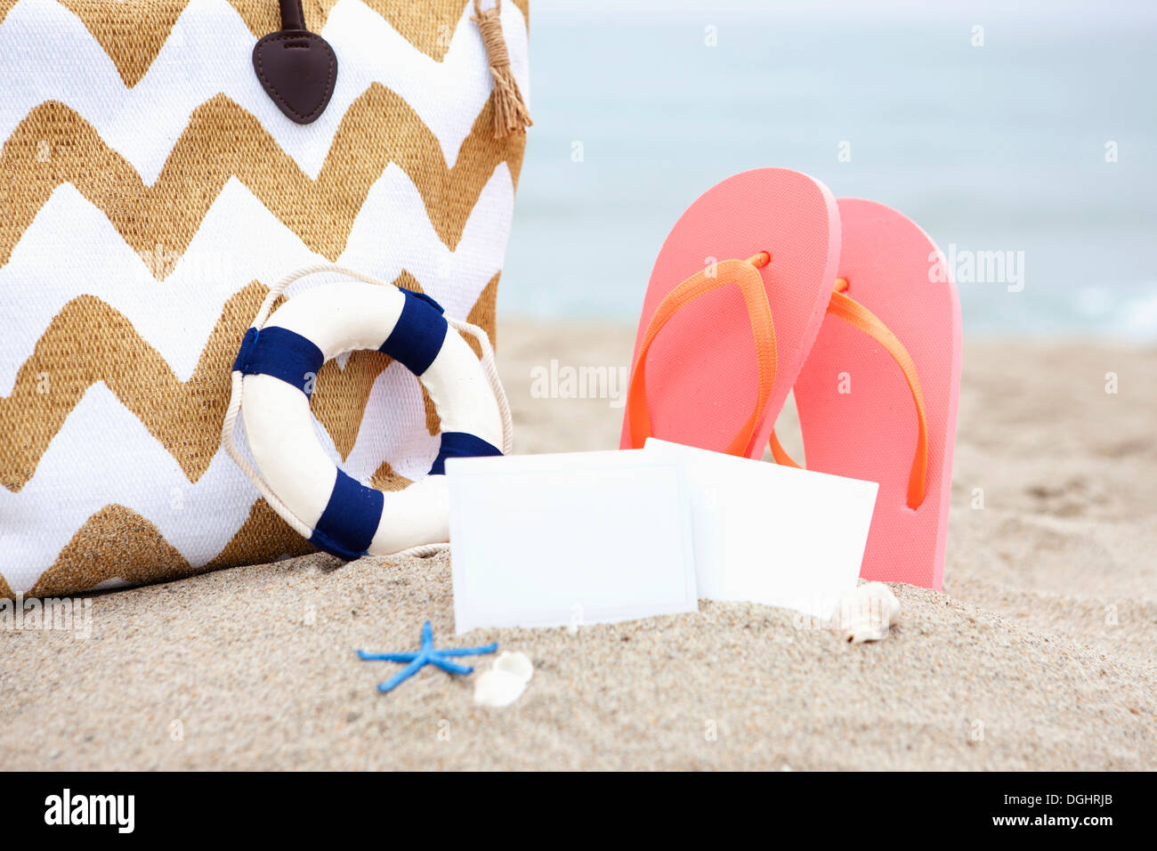 Un sacchetto e flip flop su una spiaggia Foto Stock