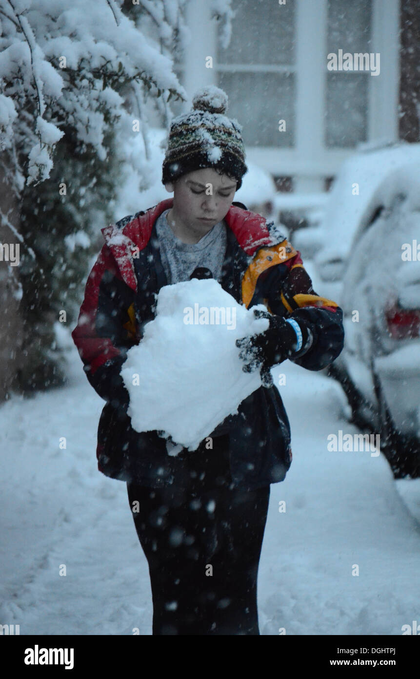 Ragazzo tenendo una grande palla di neve Foto Stock