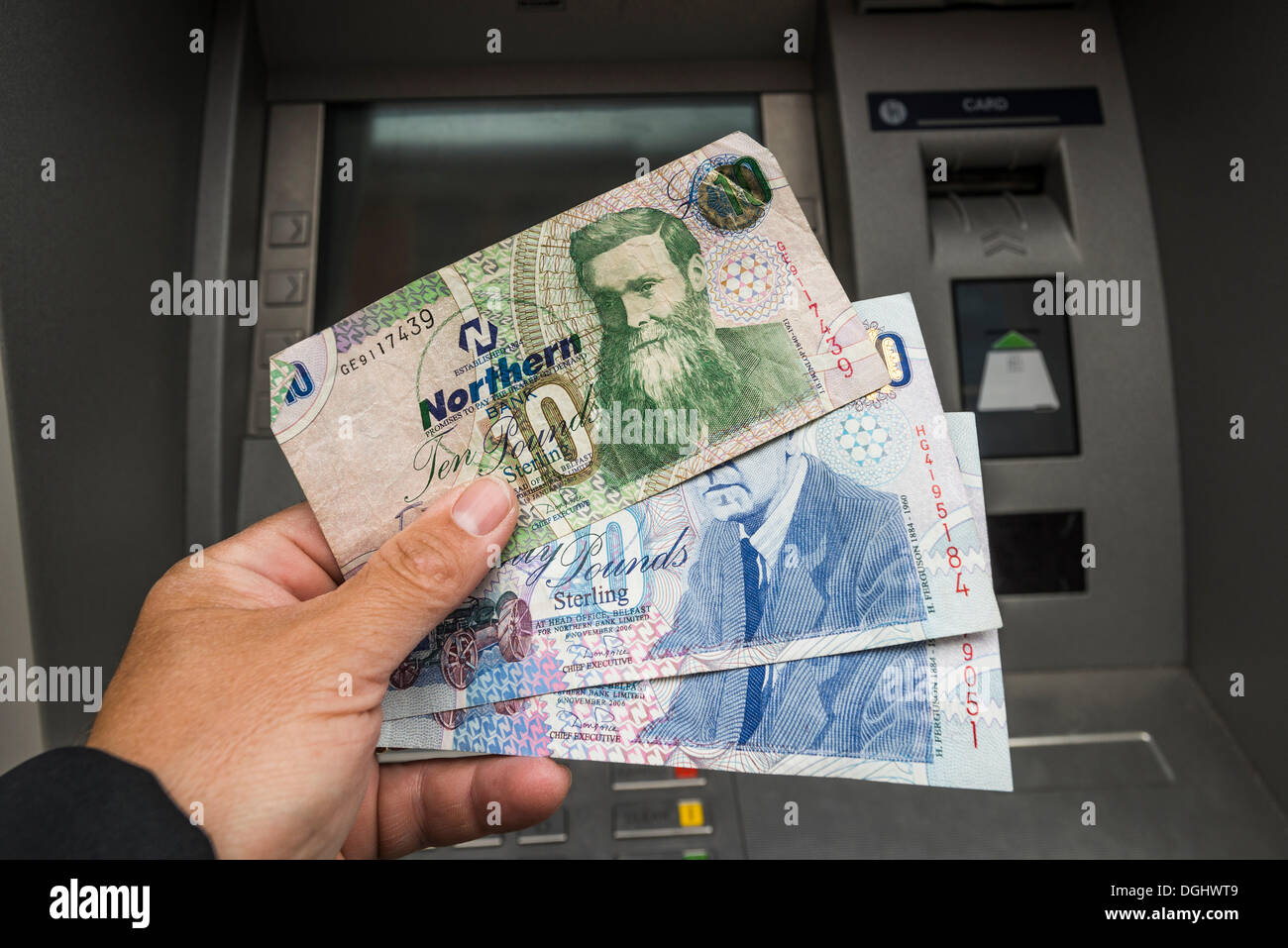 Irlanda del Nord 10 e 20 pound note tenuto in una mano davanti a un bancomat, Irlanda del Nord, Regno Unito Foto Stock
