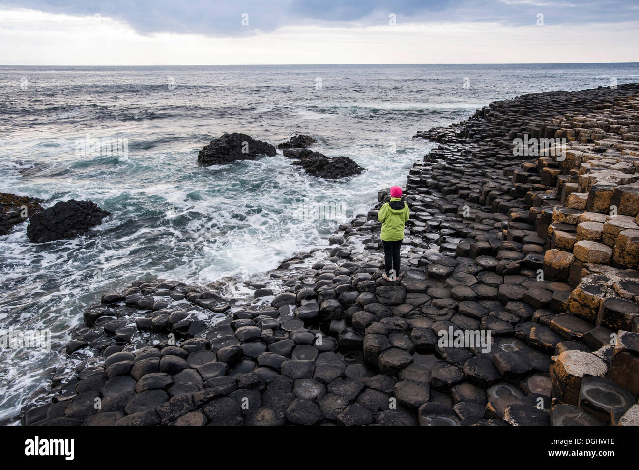 Giovane donna che guarda verso il mare e roccia basaltica, Giant Causeway, Coleraine, Irlanda del Nord, Regno Unito, Europa Foto Stock