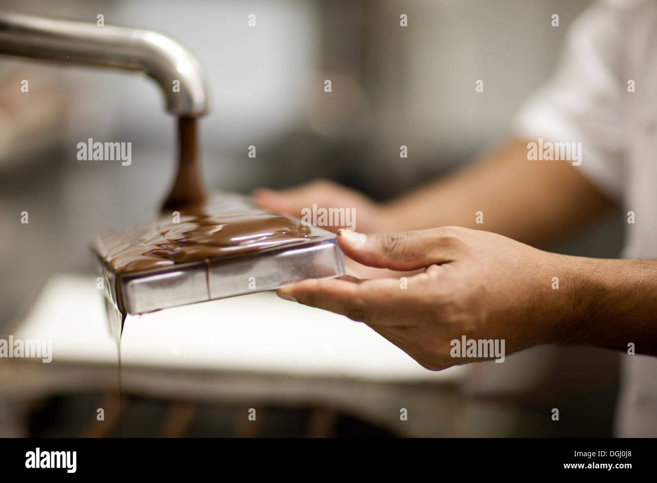 Persona che riempie lo stampo con il cioccolato fuso Foto Stock