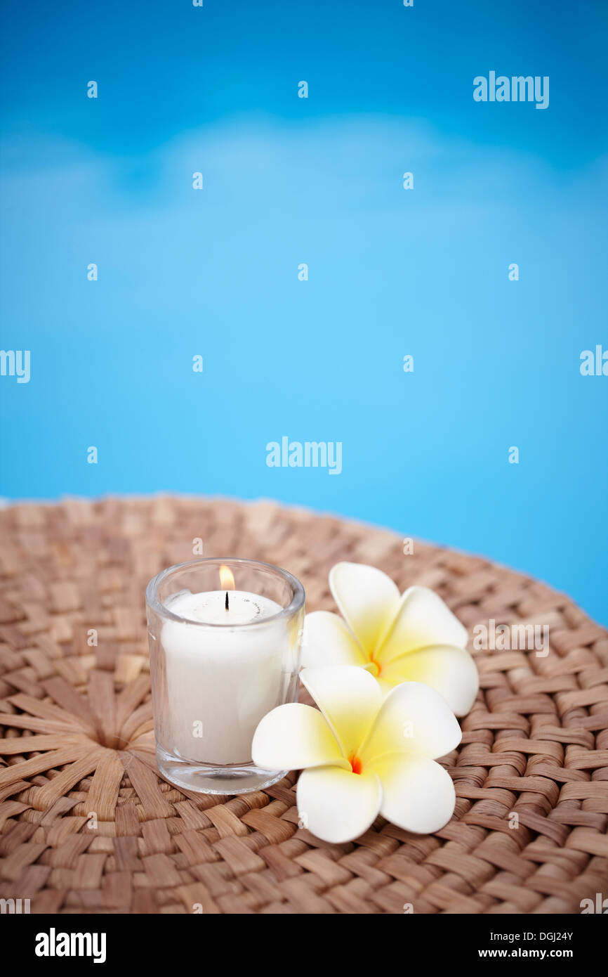 Una candela e fiori accanto alla piscina Foto Stock