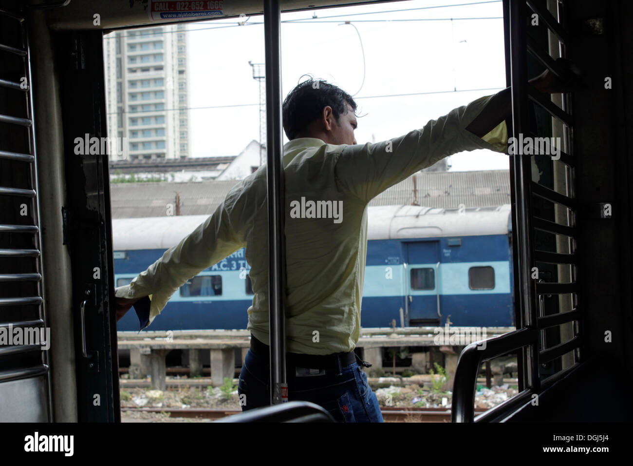 Indian giovane uomo in piedi in un treno locale mumbai Foto Stock