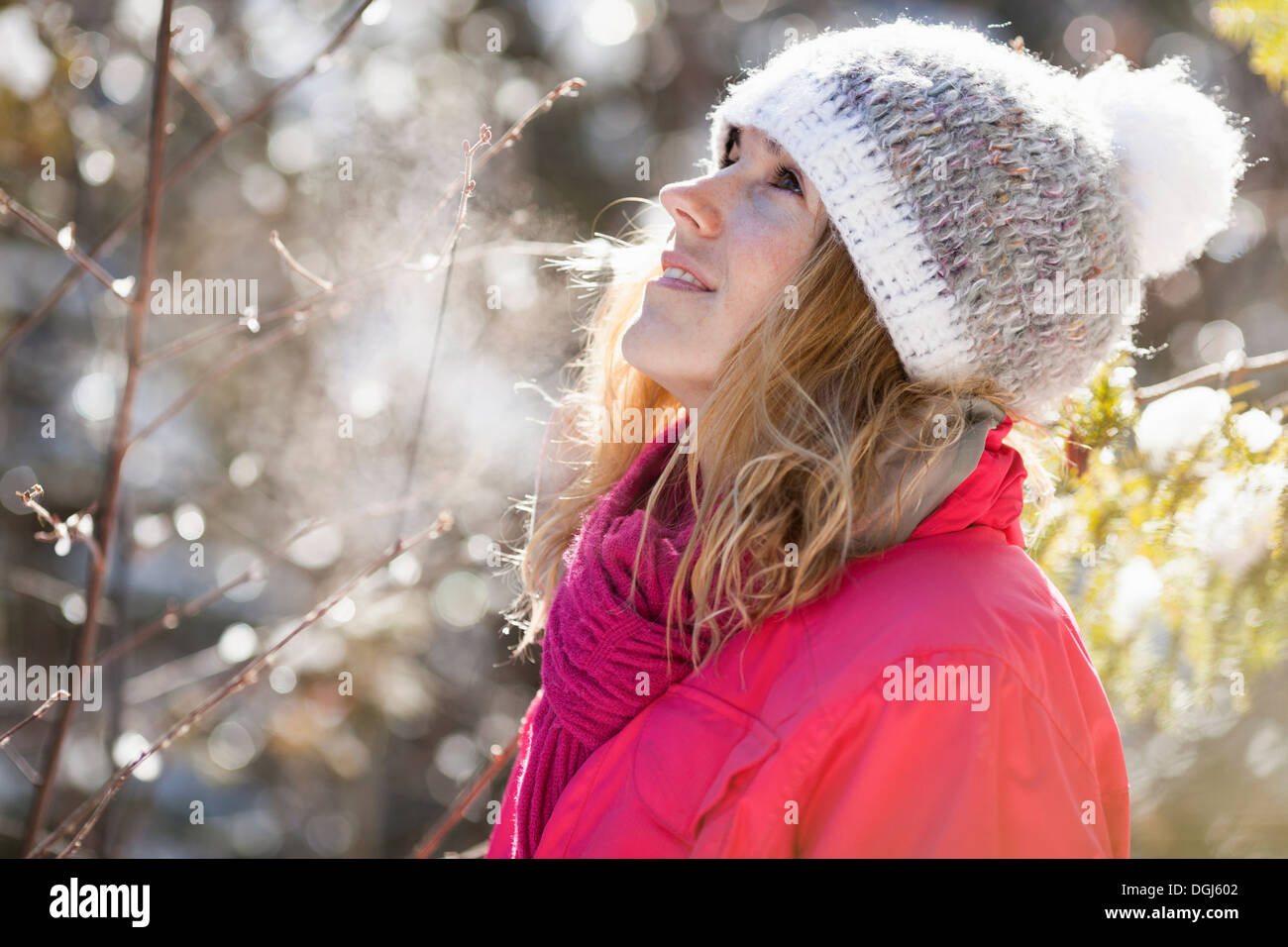 Giovane donna adulta tra coperte di neve a rami di alberi Foto Stock