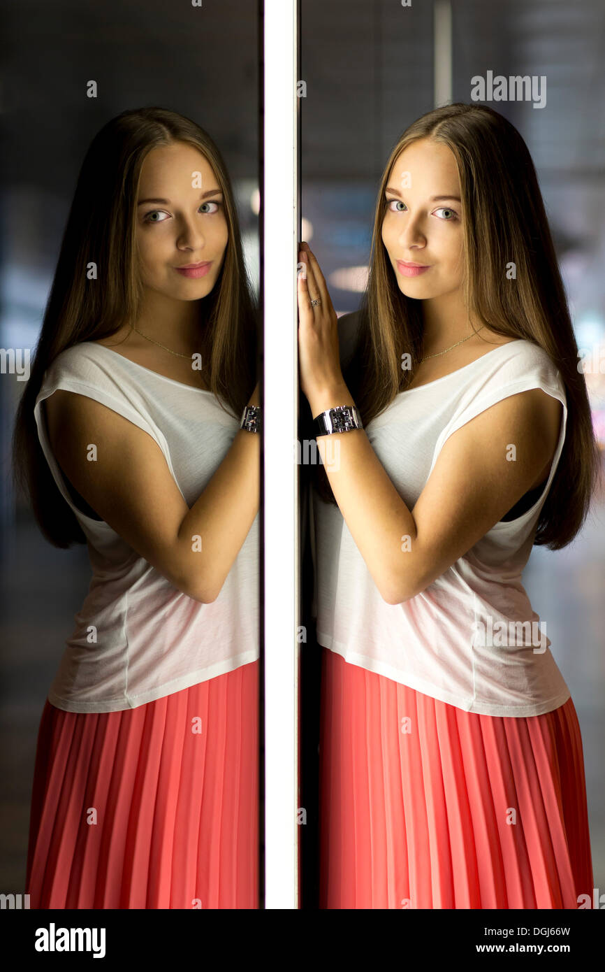 Giovane donna che indossa un top bianco e un mantello rosso, immagine speculare Foto Stock