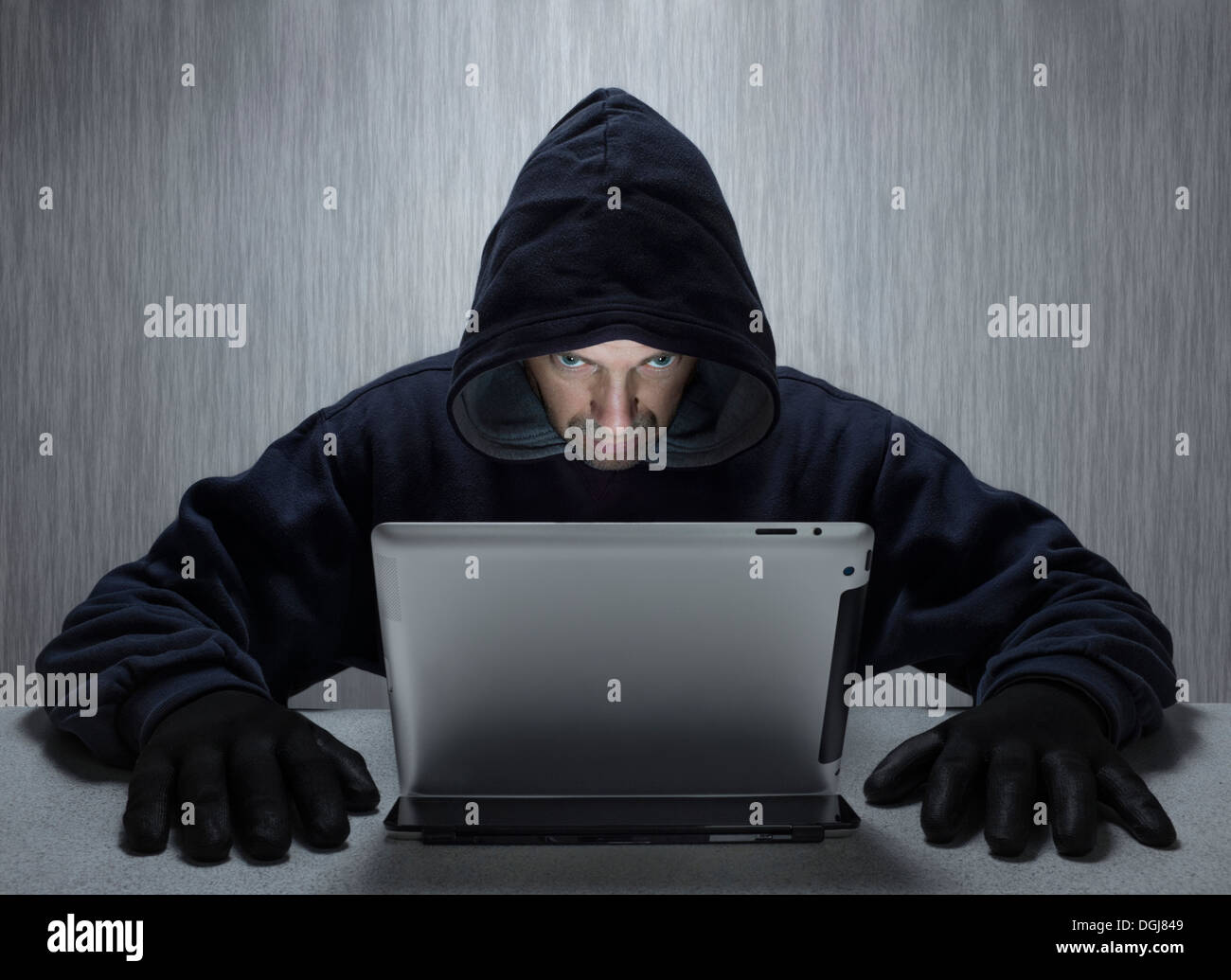 Un uomo incappucciato che rappresenta un cyber criminali. Foto Stock