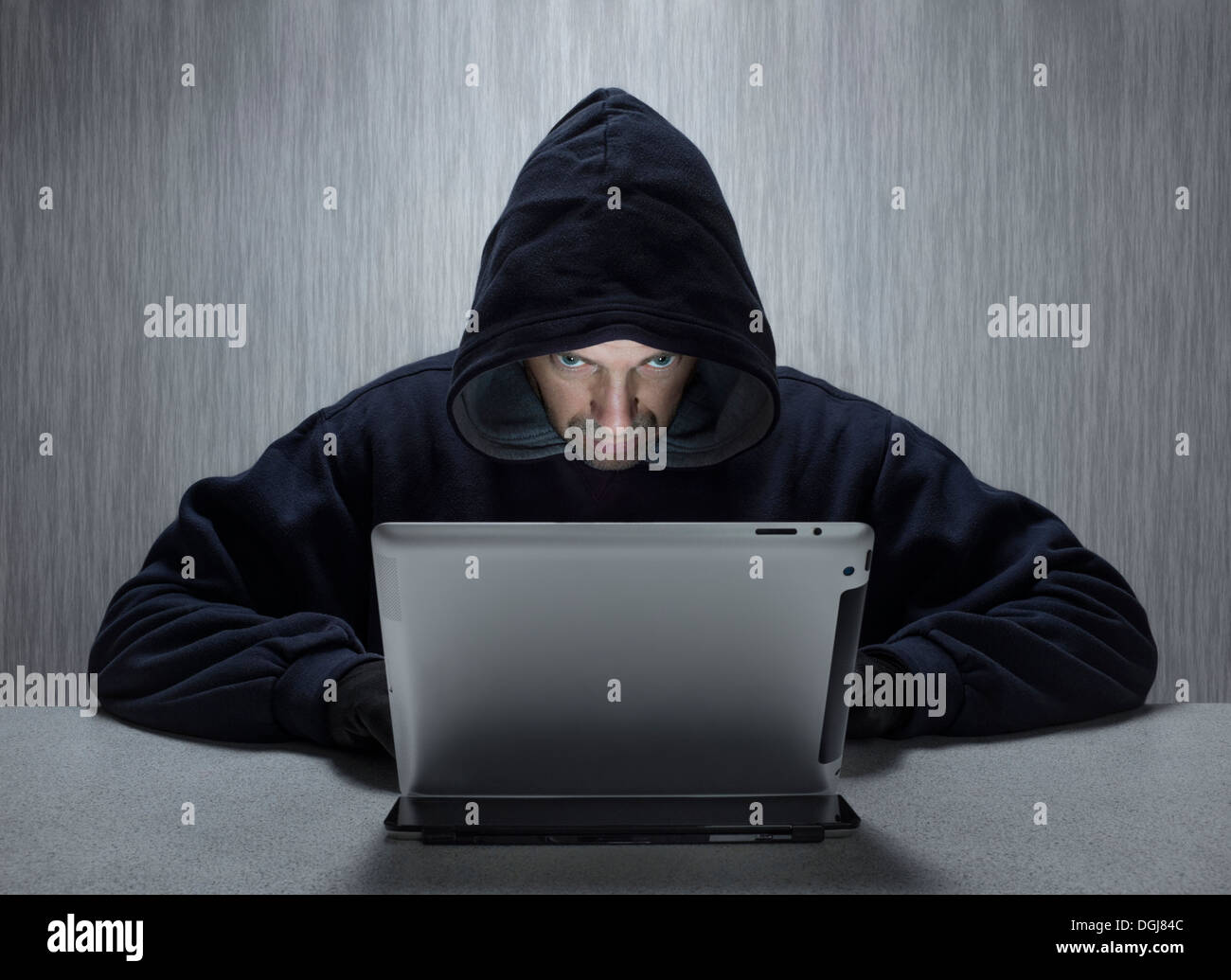 Un uomo incappucciato che rappresenta un cyber criminali. Foto Stock