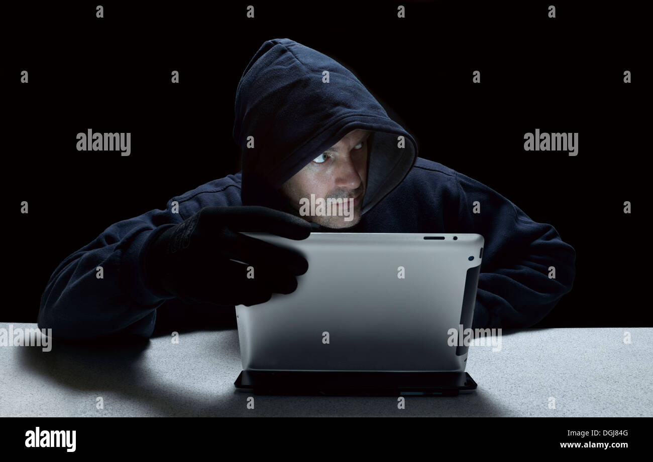 Un uomo incappucciato che rappresenta un cyber criminali. Foto Stock