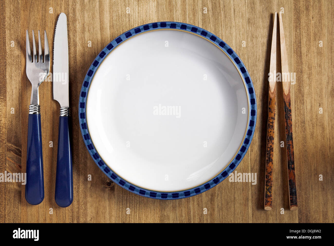 Piastra su una tabella con coltello e forchetta e bastoncini. Foto Stock