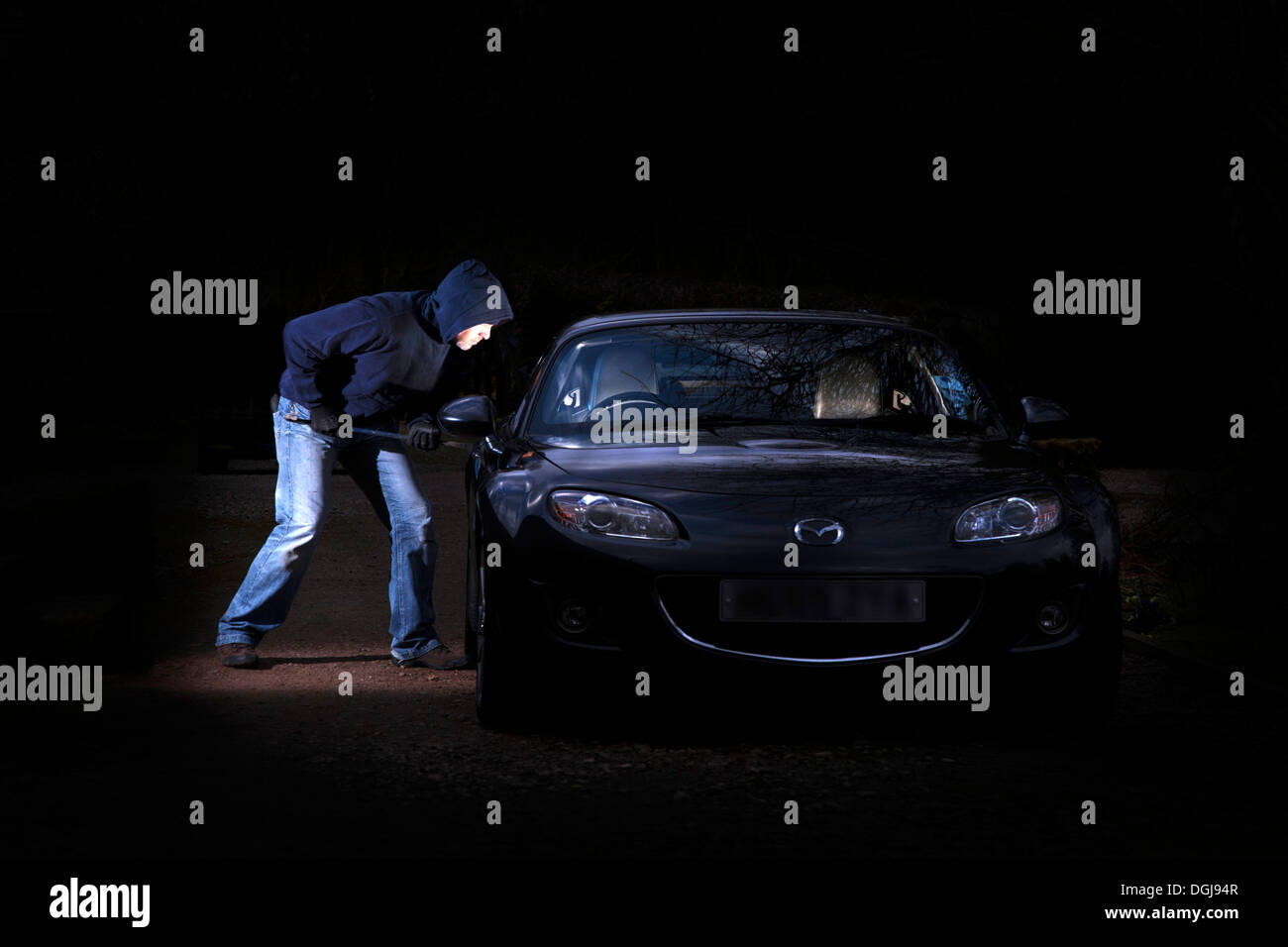 Un uomo la rottura in una macchina parcheggiata di notte. Foto Stock