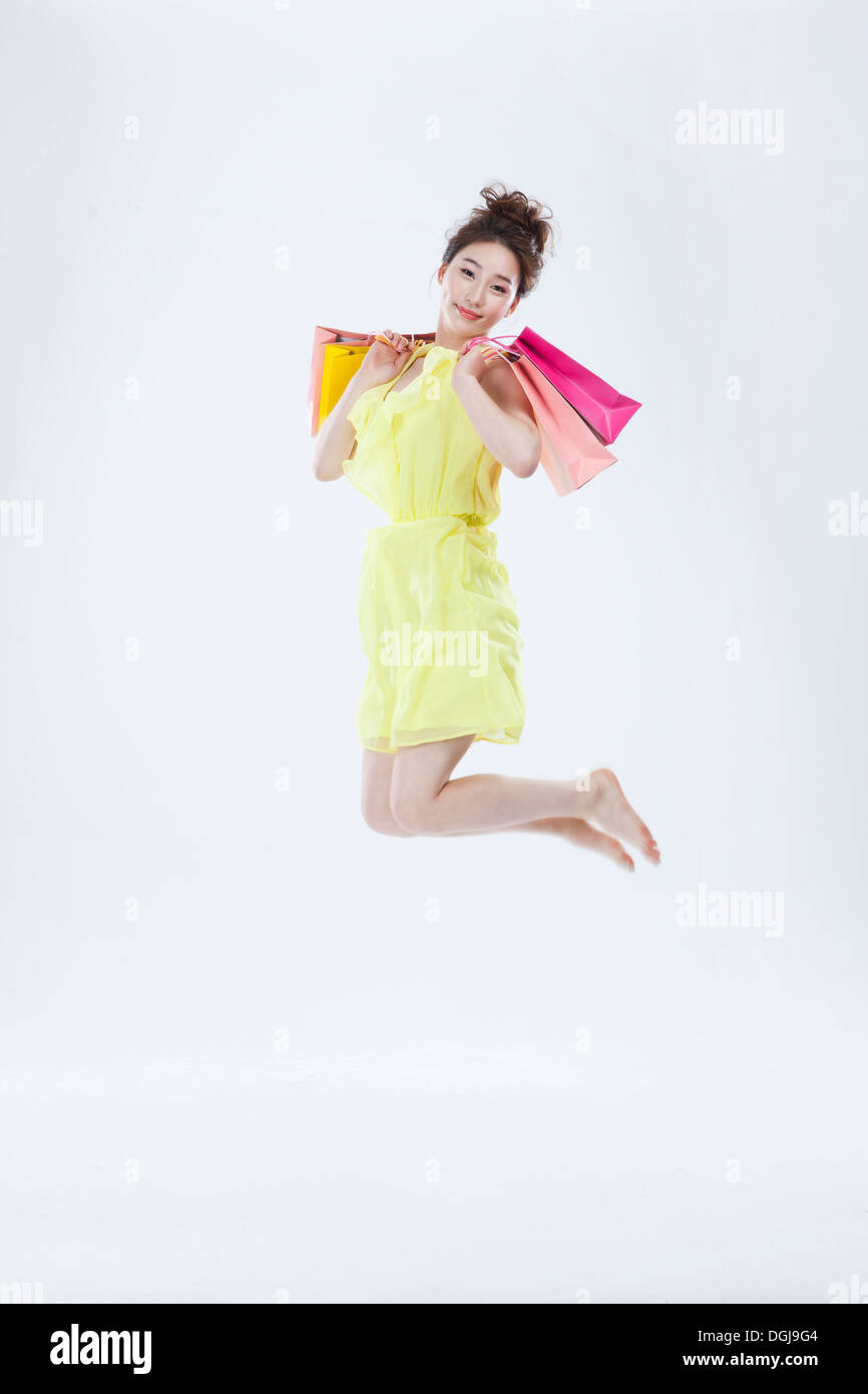 Una donna salta con le borse della spesa Foto Stock
