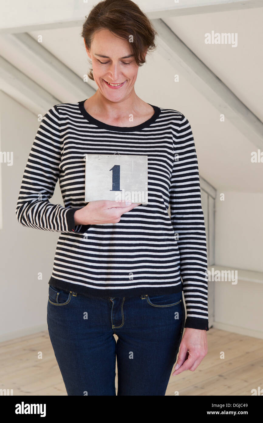Donna che mantiene il pezzo di carta con il numero 1 Foto Stock