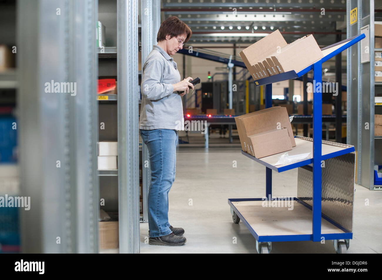 Femmina lavoratore magazzino Ordini di controllo sul carrello di distribuzione Foto Stock