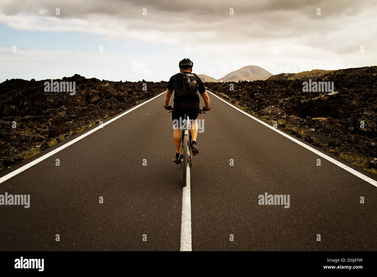 Uomo in mountain bike sulla strada, Lanzarote Foto Stock